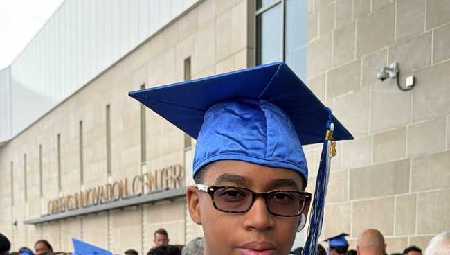 Liam standing in graduation cap and gown